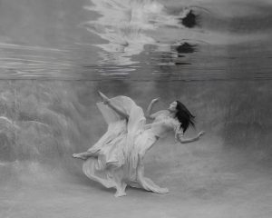 A woman wears a bumble gum pink skirt while floating to the surface during her photoshoot at our underwater studio in Jacksonville, Florida.
